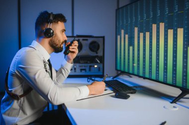 Gizli ajan kayıt cihazını dinliyormuş. Memur kulaklıkla dinleme yapıyor..