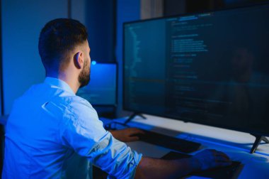 Bilgisayarda çalışan bilişim programcısı. Erkek Uzman Yaratıcı Yenilikçi Yazılım Mühendisliği Geliştirme Uygulaması, Program, Video Oyunu. Kodlama Dili Terminali. Omuz üstünden.