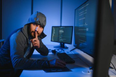 Bilgisayarlı bir hacker, kapüşonlu bir masada oturan bir adam..