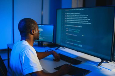 Bilgisayarda çalışan bilişim programcısı. Erkek Uzman Yaratıcı Yenilikçi Yazılım Mühendisliği Geliştirme Uygulaması, Program, Video Oyunu. Kodlama Dili Terminali. Omuz üstünden.