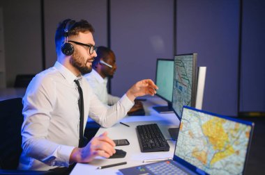Tamirat merkezi. Seyrüsefer kontrol panosunda otururken mikrofonla çalışan bir adamın portresi.