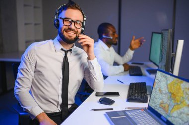 Tamirat merkezi. Seyrüsefer kontrol panosunda otururken mikrofonla çalışan erkeklerin portresi.