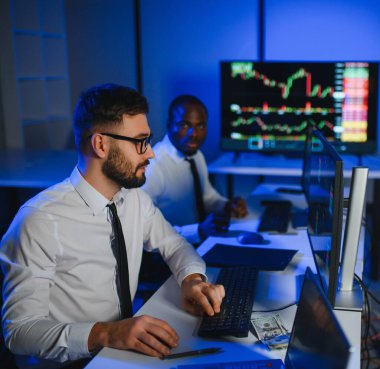 Finansal Analizci İş Gecesinde Yatırım Bankeriyle Konuşuyor. Çoklu Monitör Çalışma İstasyonunda Gerçek Zaman Stok Çizelgesi Verisi Hakkında Sohbet