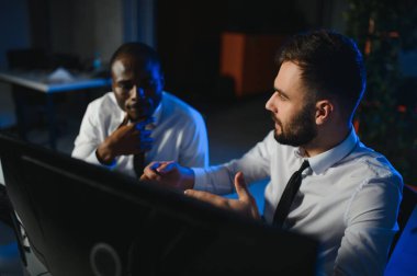 Finansal Analizci İş Gecesinde Yatırım Bankeriyle Konuşuyor. Çoklu Monitör Çalışma İstasyonunda Gerçek Zaman Stok Çizelgesi Verisi Hakkında Sohbet