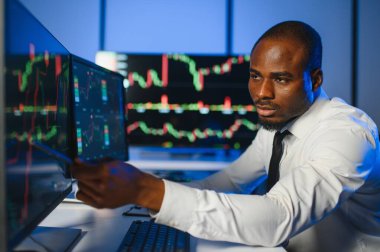 Gerçek zamanlı hisse senetleri, emtialar ve borsa grafikleri ile birlikte Multi-Monitor Workstation ile bilgisayar üzerinde çalışan finansal analist. Afrikalı Amerikalı İşadamı Gece Yatırım Bankası 'nda çalışıyor.