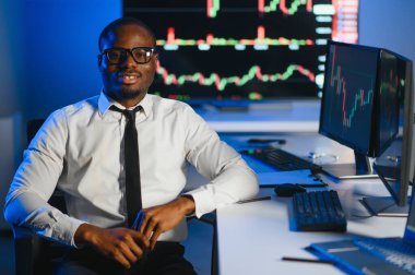 Gerçek zamanlı hisse senetleri, emtialar ve borsa grafikleri ile birlikte Multi-Monitor Workstation ile bilgisayar üzerinde çalışan finansal analist. Afrikalı Amerikalı İşadamı Gece Yatırım Bankası 'nda çalışıyor.