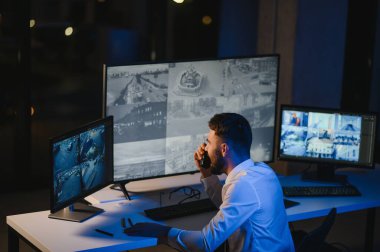 Güvenlik kamerası görüntülerini ve haritayı bilgisayarda izleyen bir adam..