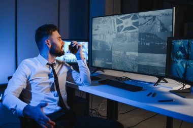 Güvenlik kamerası görüntülerini ve haritayı bilgisayarda izleyen bir adam..