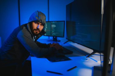 Bilgisayarlı bir hacker, kapüşonlu bir masada oturan bir adam..