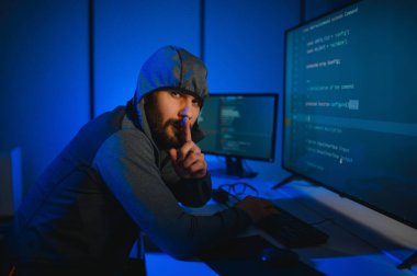 Bilgisayar programcısı karanlık odada bilgisayar kullanıyor.