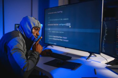 Bilgisayar programcısı karanlık odada bilgisayar kullanıyor.