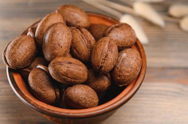 Ahşap zemin üzerinde kaynamış konsantre süt ile lezzetli fındık şekilli kurabiyeler..