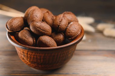 Ahşap zemin üzerinde kaynamış konsantre süt ile lezzetli fındık şekilli kurabiyeler..