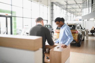 Bir araba galerisinde danışman, müşteriye yeni bir araba seçmesinde yardımcı olur..