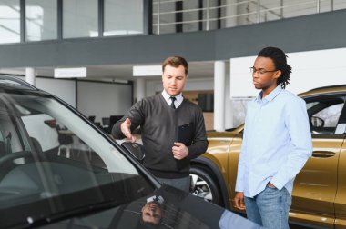 Erkek müşterinin portresi galeride profesyonel araba satıcısıyla konuşuyor. Yeni otomobil seçimi ve satın alma kavramı.