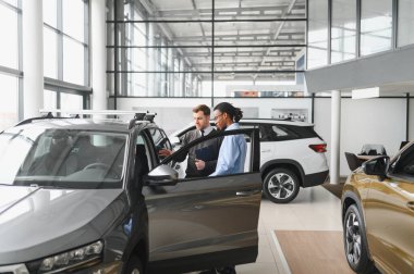 Bir araba galerisinde danışman, müşteriye yeni bir araba seçmesinde yardımcı olur..