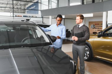 Bir araba galerisinde danışman, müşteriye yeni bir araba seçmesinde yardımcı olur..