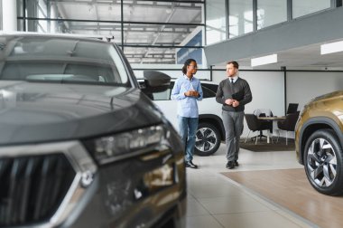 Bir araba galerisinde danışman, müşteriye yeni bir araba seçmesinde yardımcı olur..