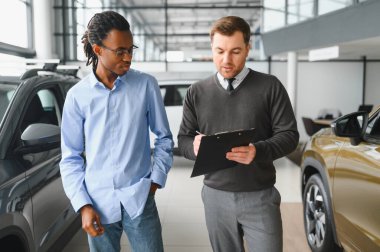 Bir araba galerisinde danışman, müşteriye yeni bir araba seçmesinde yardımcı olur..