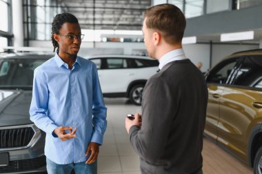 Erkek müşterinin portresi galeride profesyonel araba satıcısıyla konuşuyor. Yeni otomobil seçimi ve satın alma kavramı.