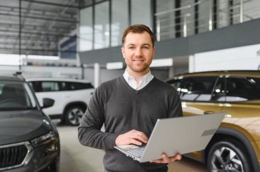 Modern araba satıcısının portresi fotokopi alanı olan bir araba salonunda duruyor..