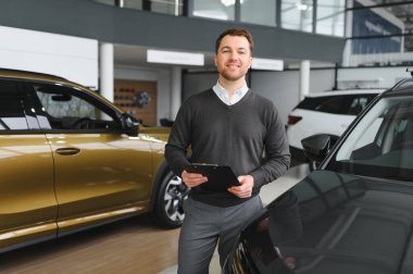 Modern araba satıcısının portresi fotokopi alanı olan bir araba salonunda duruyor..