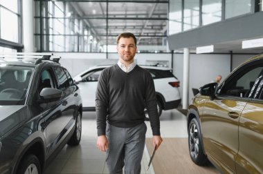 Modern araba satıcısının portresi fotokopi alanı olan bir araba salonunda duruyor..