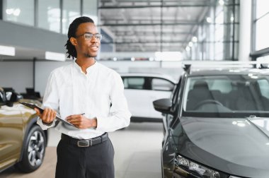Modern araba satıcısının portresi fotokopi alanı olan bir araba salonunda duruyor..