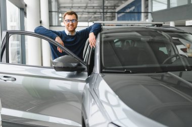 Bugün yeni bir araba aldım. Yerel bayilikte yeni arabasının yanında poz veren mutlu, olgun bir adamın portresi..