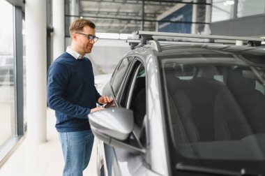 Bugün yeni bir araba aldım. Yerel bayilikte yeni arabasının yanında poz veren mutlu, olgun bir adamın portresi..