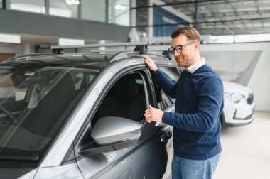 Bugün yeni bir araba aldım. Yerel bayilikte yeni arabasının yanında poz veren mutlu, olgun bir adamın portresi..