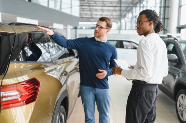 Erkek müşterinin portresi galeride profesyonel araba satıcısıyla konuşuyor. Yeni otomobil seçimi ve satın alma kavramı.