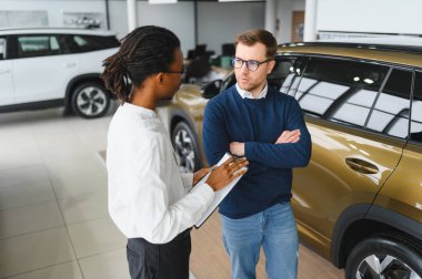 Erkek müşterinin portresi galeride profesyonel araba satıcısıyla konuşuyor. Yeni otomobil seçimi ve satın alma kavramı.