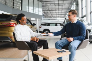 Kafkasyalı satış temsilcisi ve Afrikalı müşteri bayilikte el sıkışırken, satışı kabul ettiler..