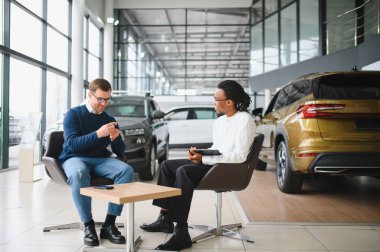 Adamın biri yeni bir arabanın anahtarlarını tutuyor. Arabayı almak için bir satıcıyla sözleşme imzalandı..