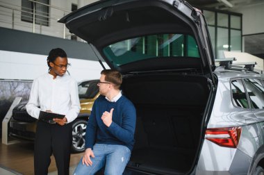 Bir araba galerisinde danışman, müşteriye yeni bir araba seçmesinde yardımcı olur..