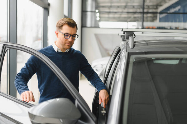 Young man is choosing a new vehicle in car dealership.