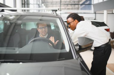 Bir araba galerisinde danışman, müşteriye yeni bir araba seçmesinde yardımcı olur..