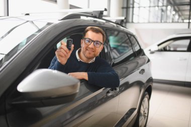 Genç adam yeni bir araç içinde araba Bayilik seçmektir.