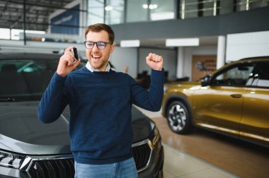 Genç adam yeni bir araç içinde araba Bayilik seçmektir.