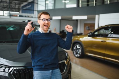 Bugün yeni bir araba aldım. Yerel bayilikte yeni arabasının yanında poz veren mutlu, olgun bir adamın portresi..