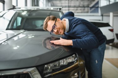 Genç adam yeni bir araç içinde araba Bayilik seçmektir.