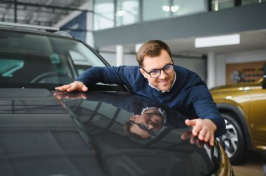 Bugün yeni bir araba aldım. Yerel bayilikte yeni arabasının yanında poz veren mutlu, olgun bir adamın portresi..