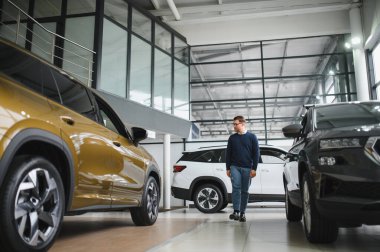 Genç adam yeni bir araç içinde araba Bayilik seçmektir.