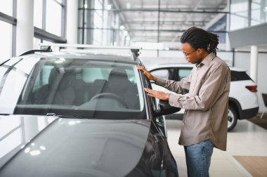 Yerel bayilikte yeni arabasının yanında poz veren mutlu bir Afrikalı adamın portresi..