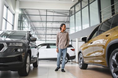 Genç Afrikalı Amerikalı adam araba galerisinde yeni bir araç seçiyor..