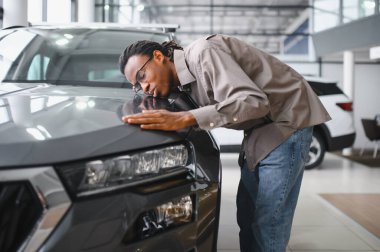 Yerel bayilikte yeni arabasının yanında poz veren mutlu bir Afrikalı adamın portresi..