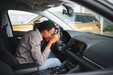 Genç yakışıklı bir adam araba galerisinde araba seçiyor..