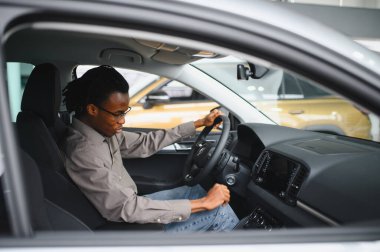 Genç adam yeni bir araç içinde araba Bayilik seçmektir.