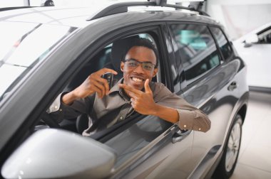 Genç Afrikalı Amerikalı adam araba galerisinde yeni bir araç seçiyor..